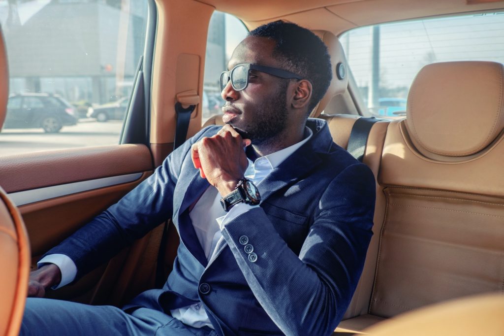 Blackman in a suit in the car.